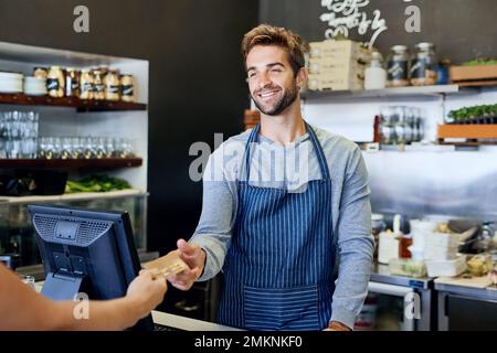 Service with a smile. a handsome young businessman taking payment from a customer. Stock Photo