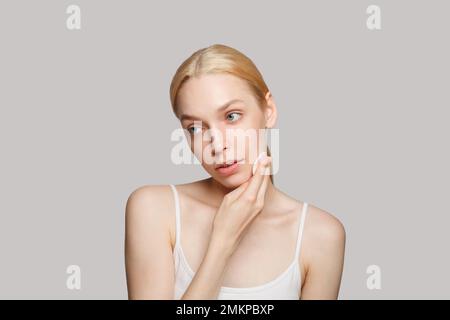 Evening routine concept. Young blonde woman is removing makeup using cotton pad Stock Photo