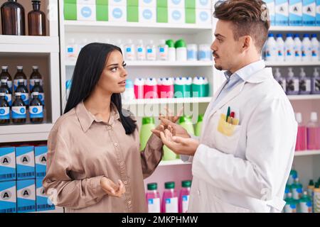 Man and woman pharmacist and client speaking at pharmacy Stock Photo