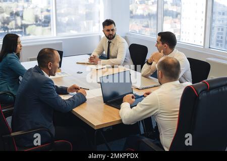 Group of young business people working and communicating while sitting at the office desk together with colleagues sitting. business meeting Stock Photo