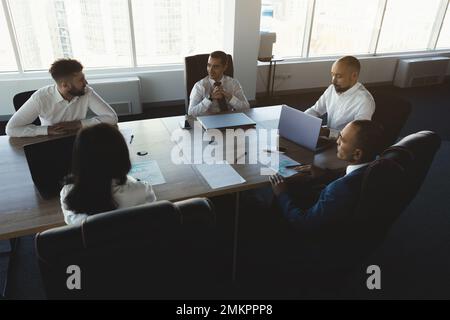 Silhouettes of people sitting at the table. Team of young business people working and communicating together in a modern office. Corporate team and Stock Photo