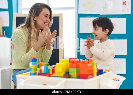 Teacher and toddler playing with construction applauding at kindergarten Stock Photo