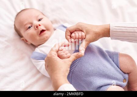 Mother and son lying on bed holding hands at bedroom Stock Photo