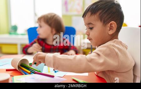 Two kids preschool students sitting on table drawing on paper at kindergarten Stock Photo