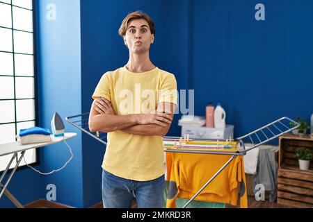 Young man doing laundry making fish face with mouth and squinting eyes, crazy and comical. Stock Photo