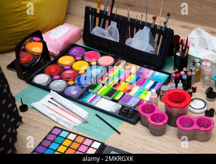 Colourful paint boxes and tubes with paints on a table. Paints and brushes for make-up, for painting on faces, face painting, face art. Abstract backg Stock Photo