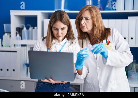 Mother and daughter scientists using laptop working at laboratory Stock Photo