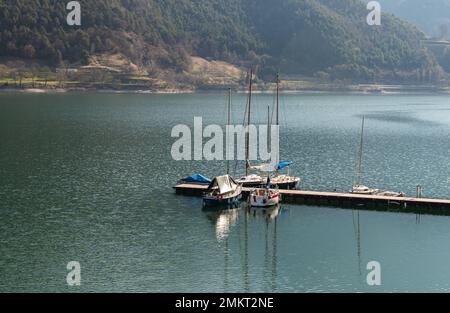 Lake Ledro (Ledro Valley) and the surrounding mountains on a clear spring day. A boat landing stage and some boats. Trento,Trentino Alto Adige,Italy Stock Photo