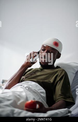 Military man with head injury talking on phone with friend or family member Stock Photo
