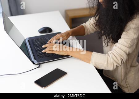 BIPOC programmer woman typing code on laptop computer. Freelancer POC works on modern notebook pc at home, shot from above Stock Photo