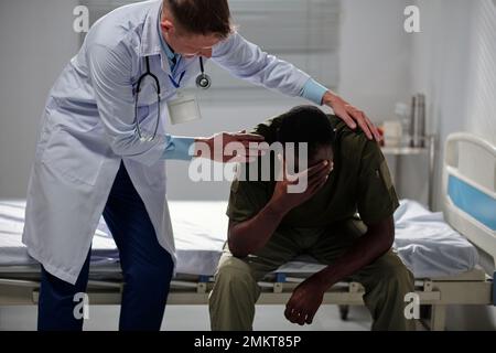Psychologist reassuring crying military man suffering from ptsd Stock Photo
