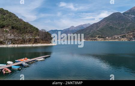 Lake Ledro (Ledro Valley) and the surrounding mountains on a clear spring day. A boat landing stage and some boats. Trento province, northern Italy Stock Photo