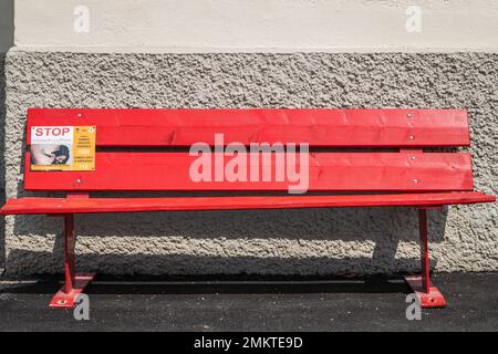A bench painted red for the International Day for the Elimination of Violence against Women in the street of Mezzolago, Ledro Valley,Trento,Italy Stock Photo