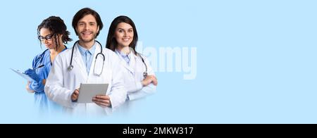 Friendly smiling multiethnic doctors posing on blue, holding digital tablet Stock Photo