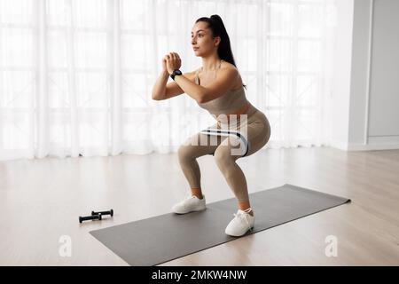 Motivated young woman doing workout at home Stock Photo