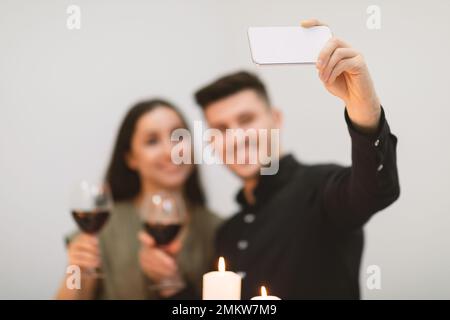 Beautiful happy young couple drinking red wine, taking selfie Stock Photo