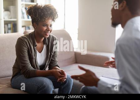 Positive african lady smiling while listening to therapist Stock Photo
