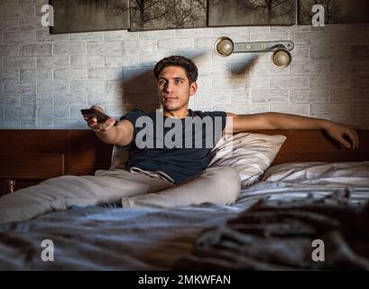 Handsome young man laying on his bed watching TV Stock Photo