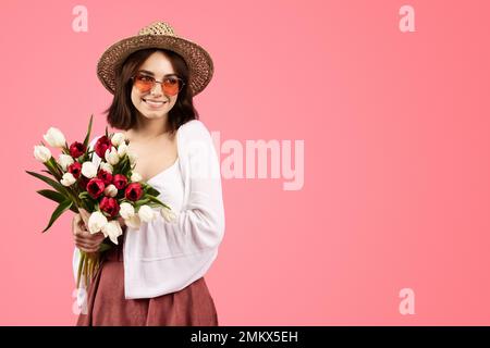 Happy pretty young caucasian woman in casual, hat and glasses with flower bouquet, enjoy birthday Stock Photo