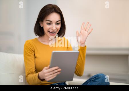 Excited young woman using digital tablet at home Stock Photo