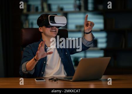 Businessman using laptop and wireless VR headset at office Stock Photo