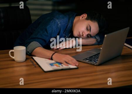 Young man manager sleeping at workdesk at office Stock Photo
