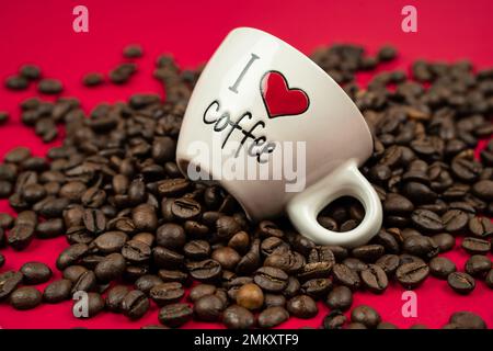 a mug filled with coffee beans on a red background with the inscription i love coffee Stock Photo