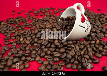 a mug filled with coffee beans on a red background with the inscription i love coffee Stock Photo