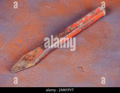 Old rusty stone chisel on a grunge orange background Stock Photo