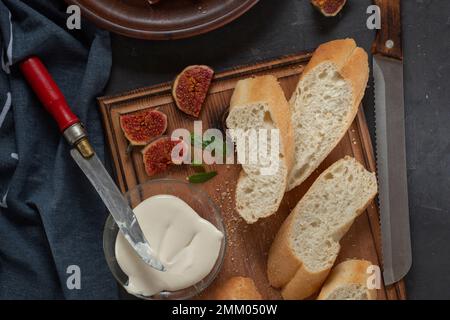 Jamon with figs and a baguette with cream cheese on the dining table, appetizer for wine, Spanish cooking. Stock Photo