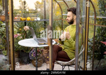 Man works remotely on laptop in garden Stock Photo