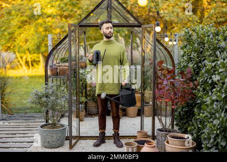 Stylish guy with watering can in garden Stock Photo