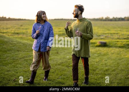 Couple hang out together, walking on green field on sunset Stock Photo