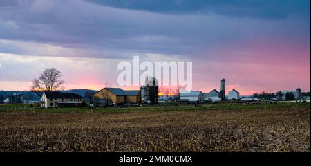 A View of a Sunset, Red Sky and Sun, With Clouds Blocking View, like a Fire in the Distance, Looking over a Farm and Farmlands Stock Photo
