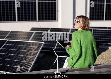 Woman monitors energy production from the solar power plant with a digital tablet Stock Photo