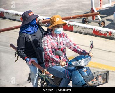 SAMUT PRAKAN, THAILAND, OCT 12 2022, A pair of female construction workers carry iron pipes on a motorbike Stock Photo