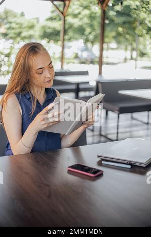 Beautiful woman with short hair sitting at the terrace on a sunny day working from home using laptop Stock Photo