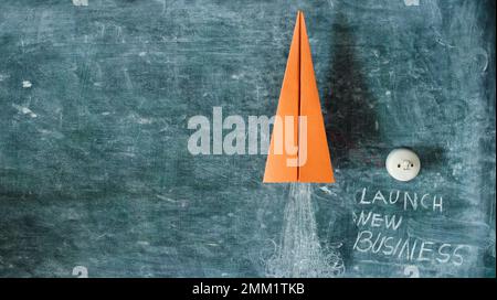 Business concept,start up, innovation and success with slogan launch new business. Launching rocket and power switch on black board. Free copy space. Stock Photo