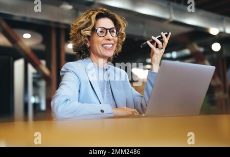 Professional woman speaking on a mobile phone in an office. Happy business woman having a phone call discussion with her associates. Mature business w Stock Photo