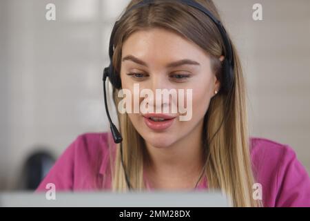 Cheerful call center operator talks to clients. Friendly online support specialist speaking with customer on a video call Stock Photo
