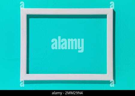 Blank white wooden frame on turquoise background. Mockup design Stock Photo