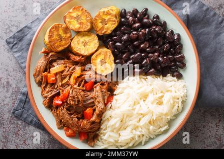 Tasty Pabellon criollo is a Venezuelan dish made with shredded beef that is typically served with white rice, black beans and fried plantains closeup. Stock Photo