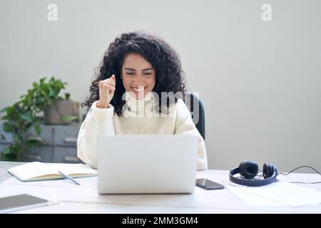 Happy young woman student or employee using laptop feeling excited. Stock Photo