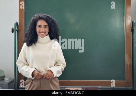 Young happy business woman coach or teacher standing at empty blackboard. Stock Photo