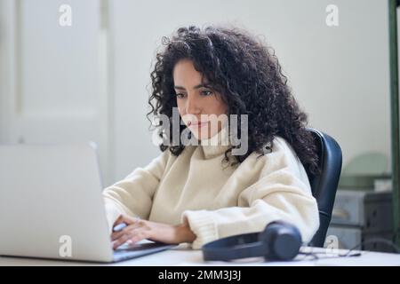 Young business woman worker sitting at office desk working on laptop. Stock Photo