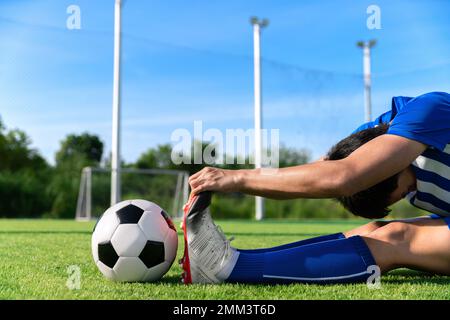 football soccer player stretching during warm up before kick ball in match league in stadium with healthy sport concept Stock Photo