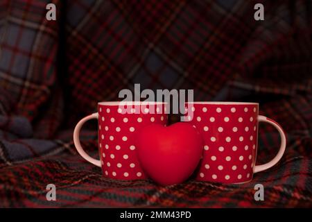 two red cups with heart on blanket. Valentine's Day background. couple of dotted mugs. copy space Stock Photo