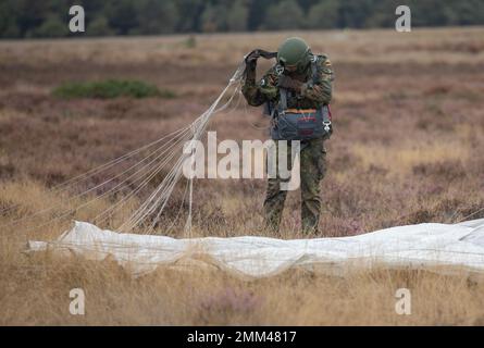 A German Paratrooper derigs his Polish parachute after landing on the Drop Zone during Exrcise Falcon Leap onto Ginkelse Heide Drop Zone, Arnhem, Netherlands., Sep. 14, 2022. More than 1000 Paratroopers from all over the world, 13 different nationalities, multiple airdrops per day, and training with each other equipment for two weeks. this is NATO's largest technical airborne exercise Stock Photo