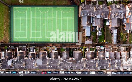 An aerial view directly above of the rooftops of back to back terraced houses in a UK suburb with a local community sports pitch for amateur use Stock Photo