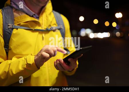 Man with backpack using mobile phone on evening city street. Stock Photo